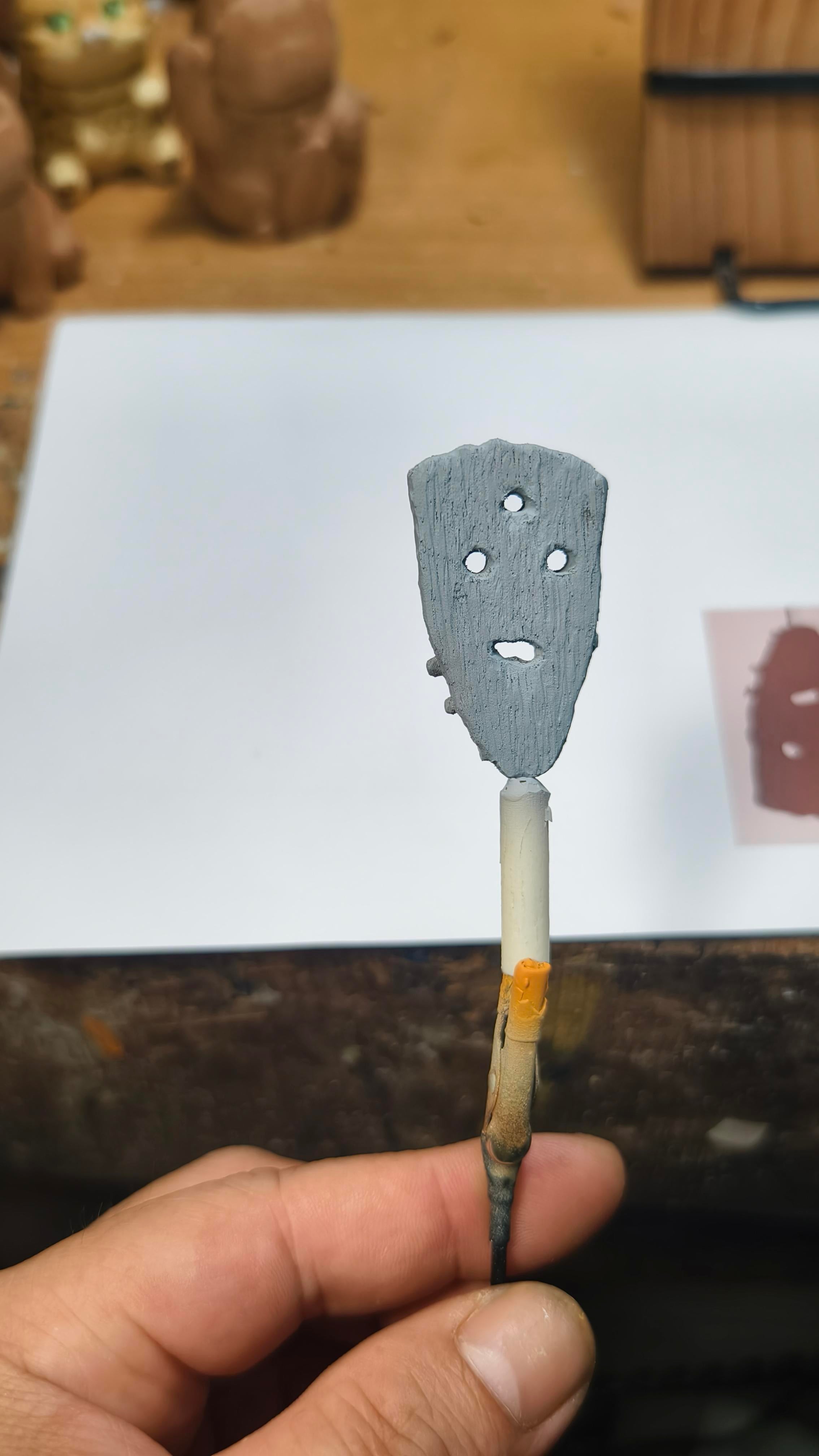 handmade spatula with holes held by a hand on a wooden surface