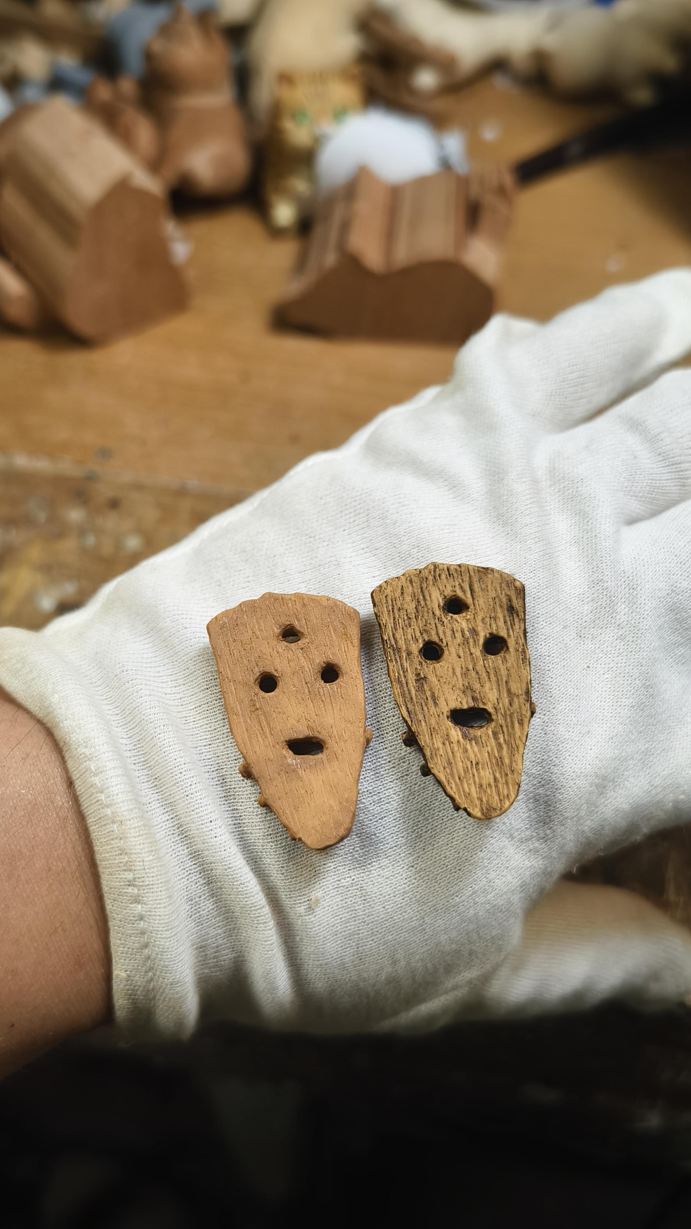 Two wooden objects with holes held by a gloved hand on a wooden surface.