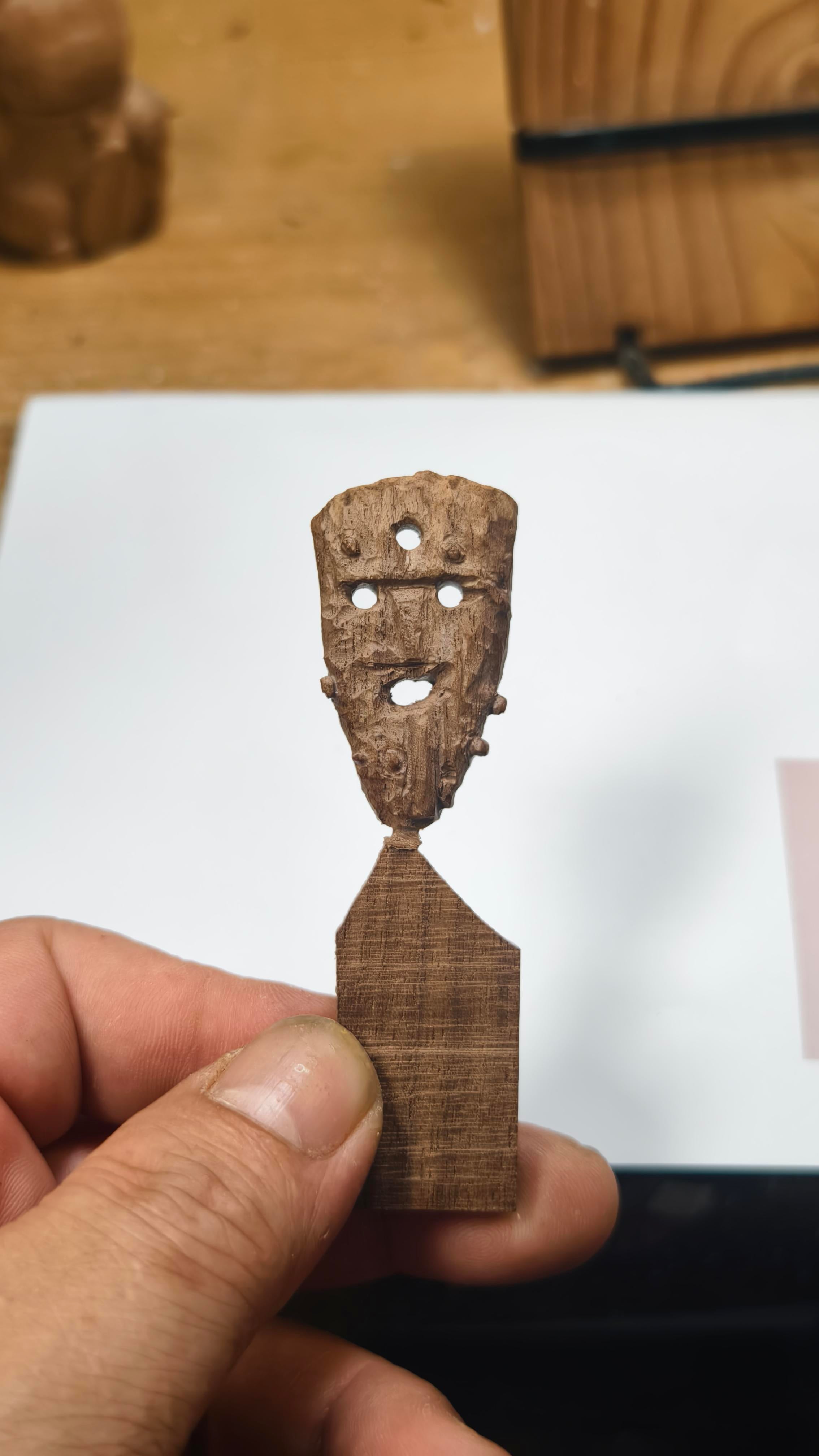 Icelandic Wooden figurine held by a hand on a light-colored surface