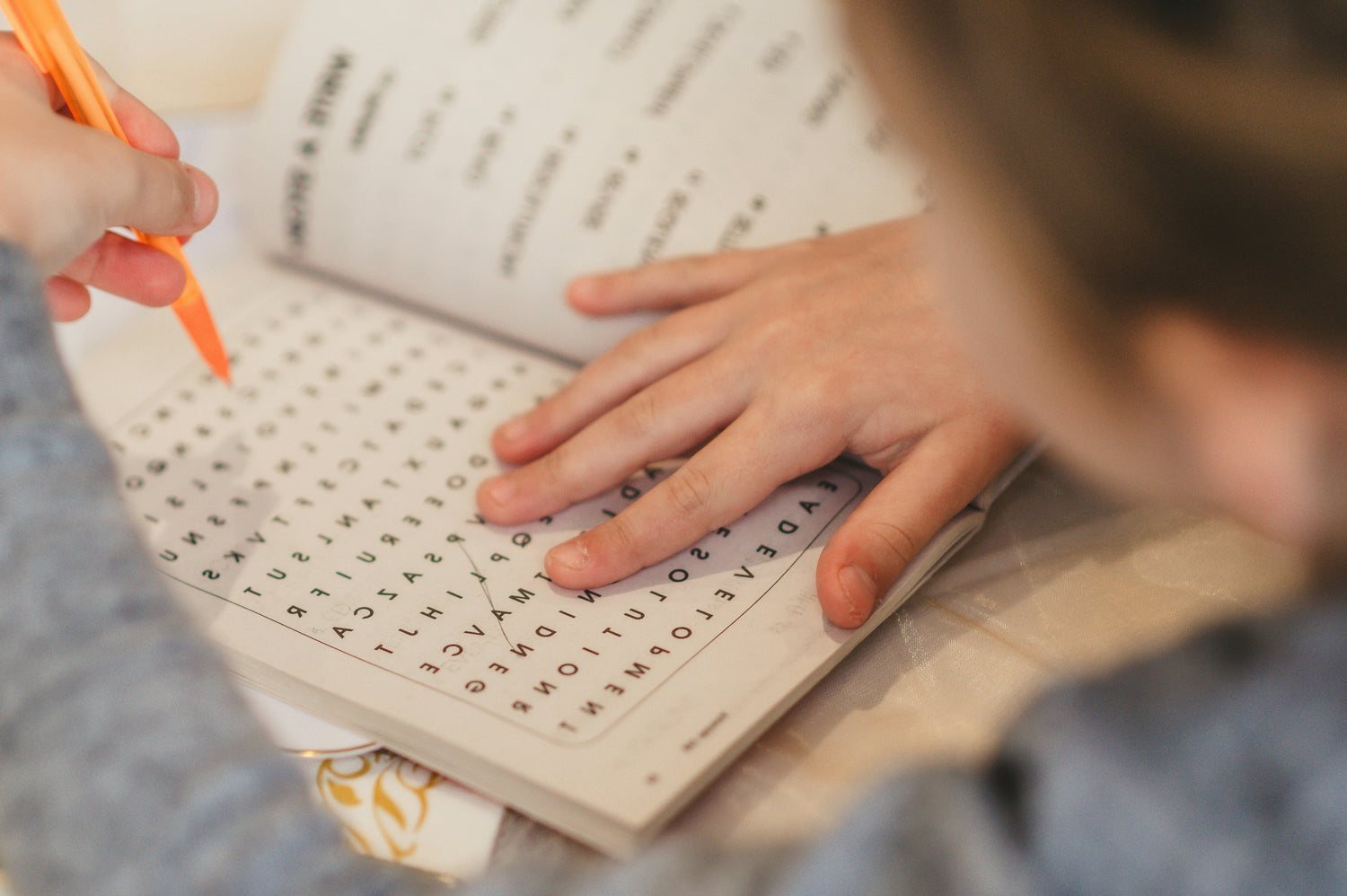 Person working on a puzzle with letters scattered on a book